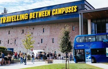 View of Penryn campus with a blue bus and the Stannary building