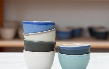 Two stacks of small ceramic bowls in white, blue and green hues.