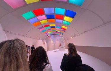 A group of people stood in a room with neon coloured ceiling panels 