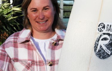 Kate with her surfboard showcasing Radical Wax branding