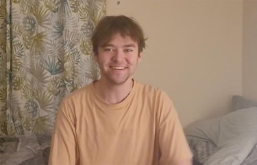 A Graphic Design student sitting in front of leaf-pattern curtains