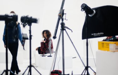 Photography studio with figure surrounded by cameras and lighting