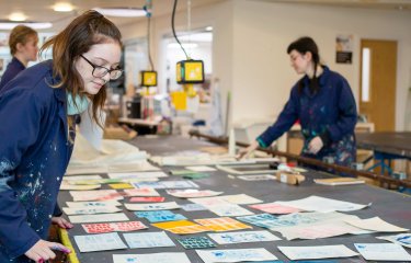 Photo of people working on textiles in a studio