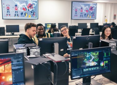 A group of people sat round computer screens