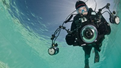A diver pictured underwater holding a large waterproof camera