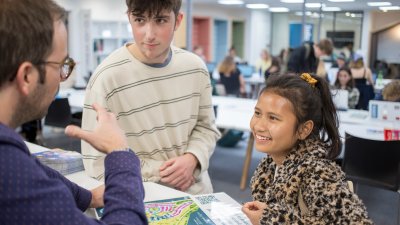 Two students speaking a staff member in The Compass