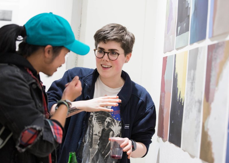 Two Falmouth University students discussing images at an exhibition.