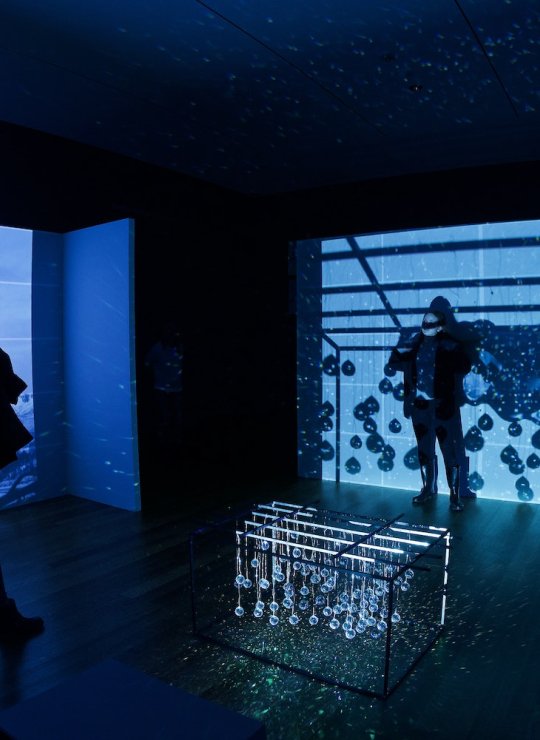 Two people standing in a dark room with blue projections