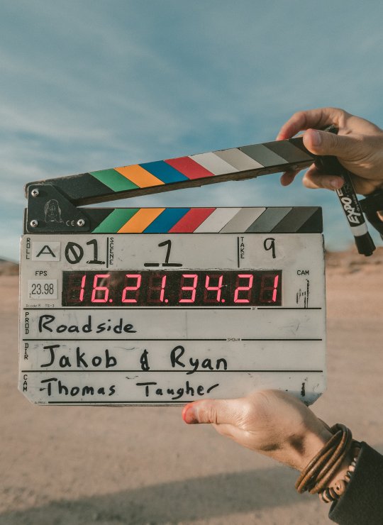 A film slate being held up against an empty field 