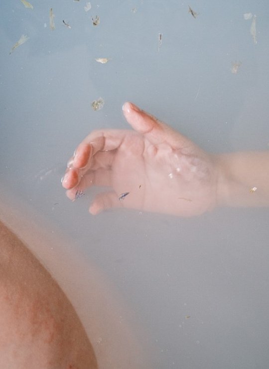 A photograph of a hand in a bathtub of water