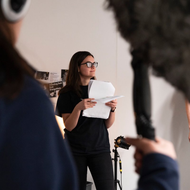 Film student standing holding pieces of paper