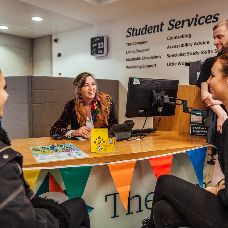 Staff and students discussing around a desk.