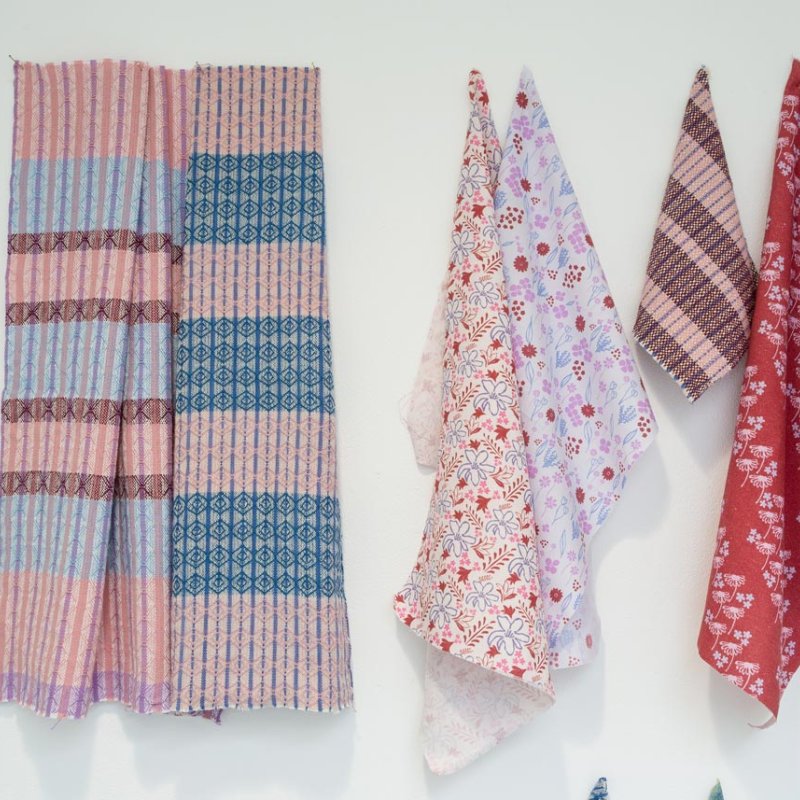 Textile samples hanging from a white wall