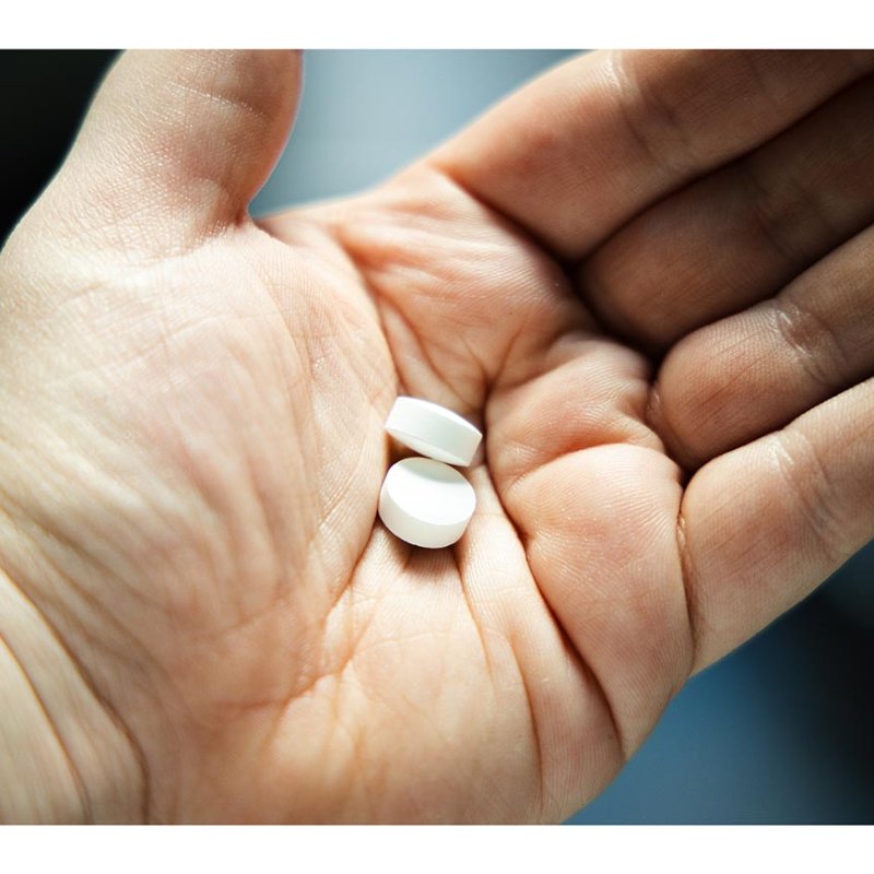 An open palm holding two white pills