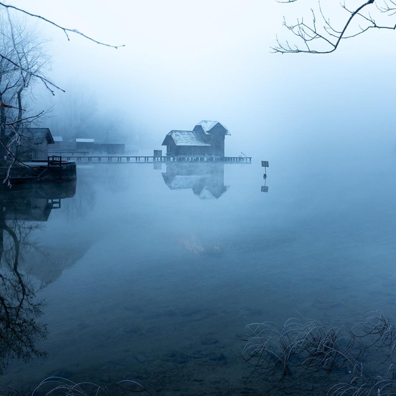 Photograph of a house on the water covered in mist