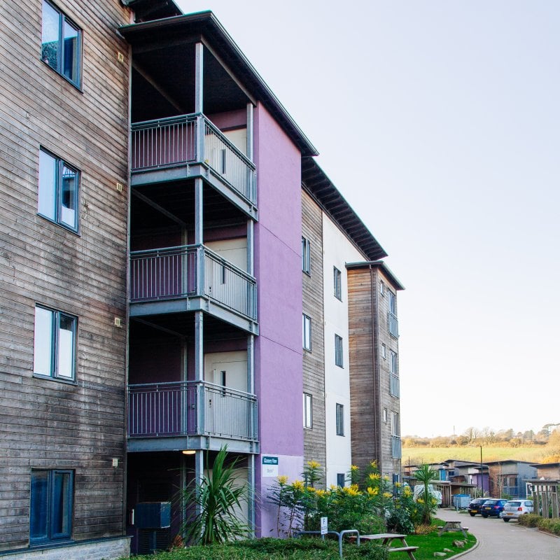 Wood panelled building with grey balconies and a purple wall