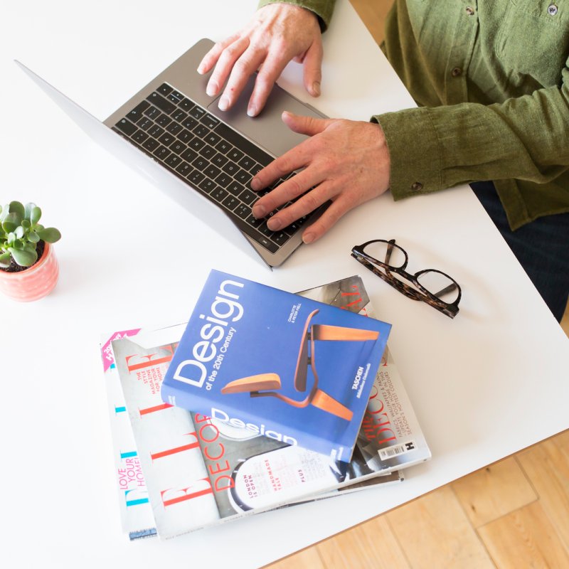 A student working at their desk with a laptop and a pile of books 