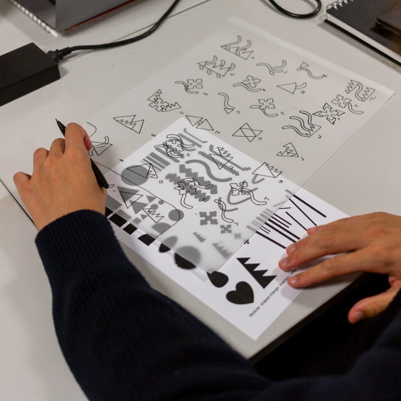 Hands framing a sheet of logos on a table