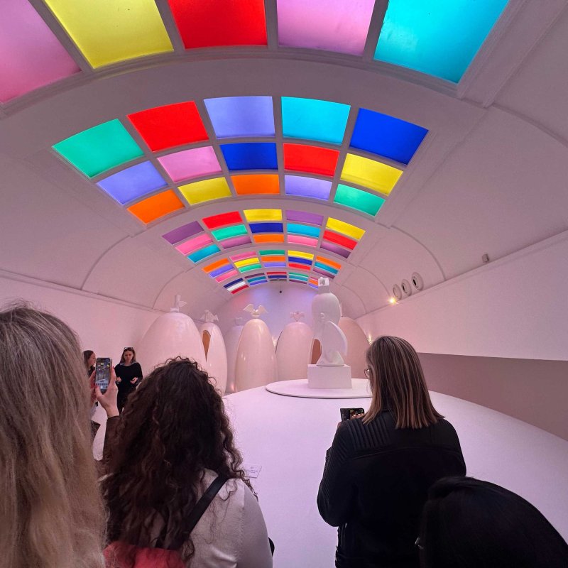 A group of people stood in a room with neon coloured ceiling panels 