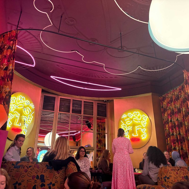 A group of people in a bar with neon wall art