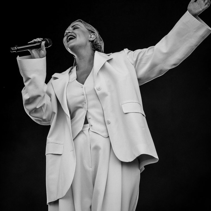 A woman wearing a white suit singing on stage 