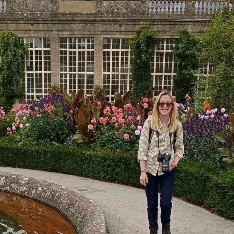 Student Lucy standing with a camera in a garden