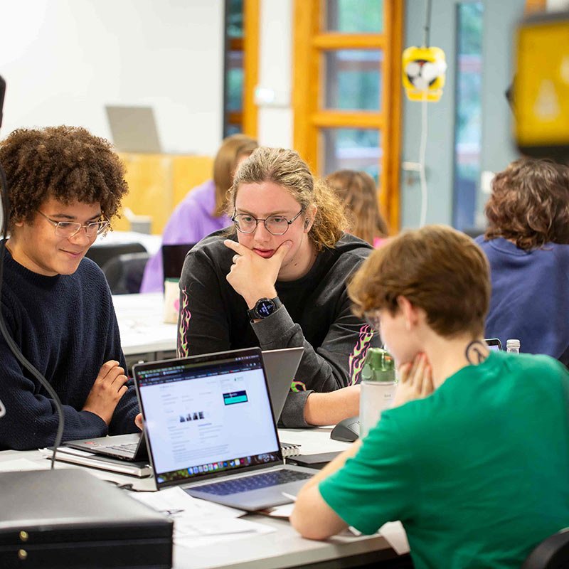 Falmouth University students sat around a laptop