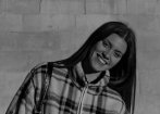 Black and white photograph of a young woman smiling, wearing a checked fleece