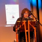 A woman stood at a pulpit reading a poem