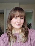 Selfie of a young woman with brown hair and pink jumper