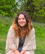 A young woman smiling with bluebells and trees in the background