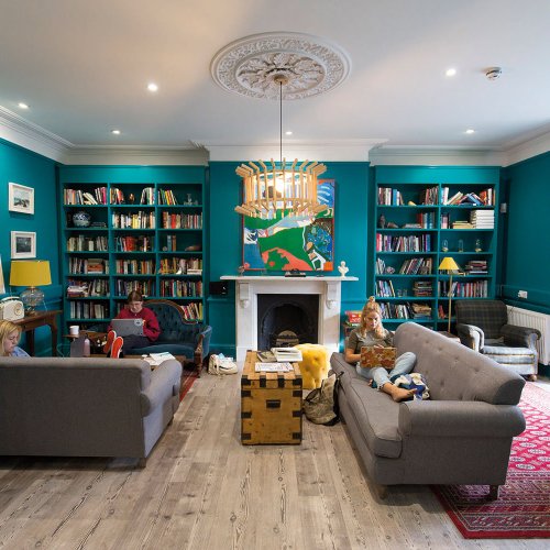 Students sat on sofa in a room full of books