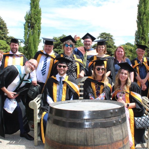 A group of graduating students wearing gowns gather together 