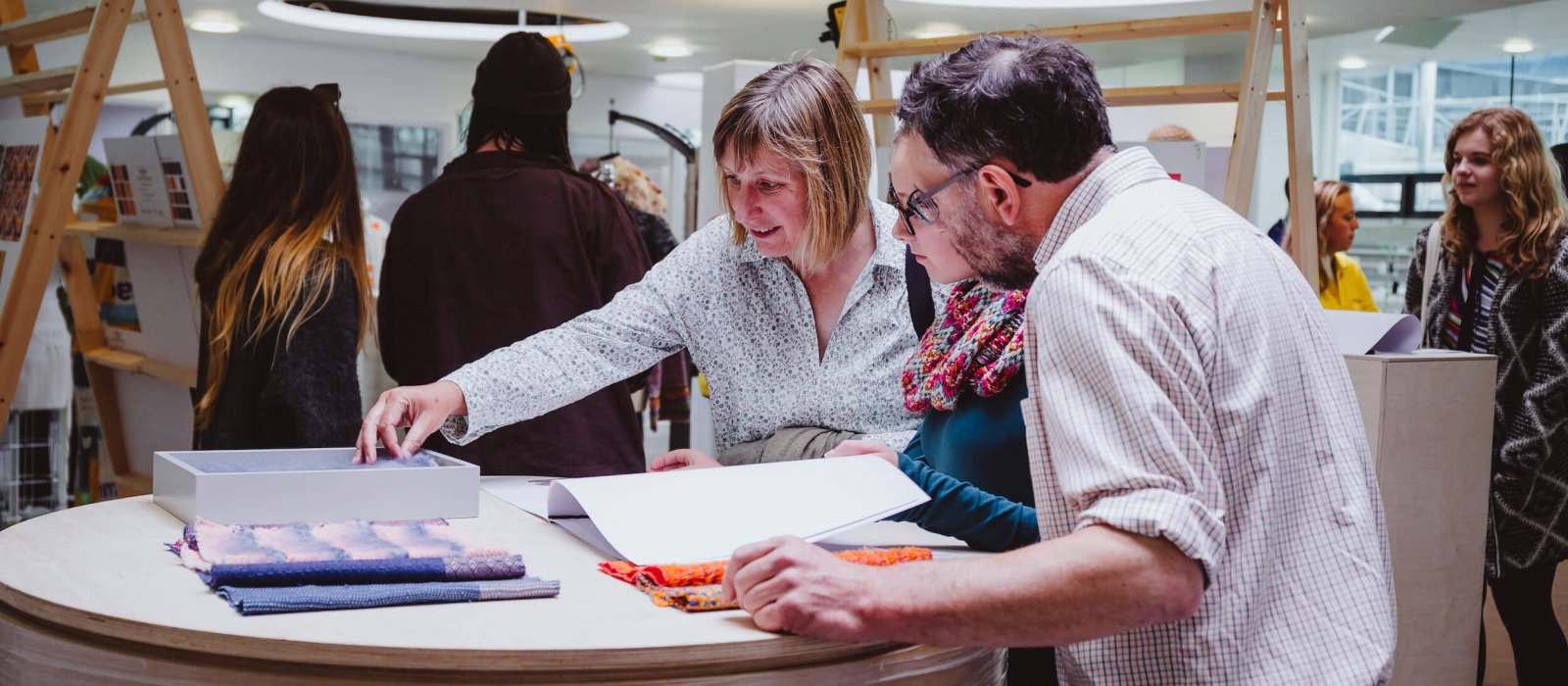 A girl with her parents looking through sketchbooks at a Falmouth University Open Day