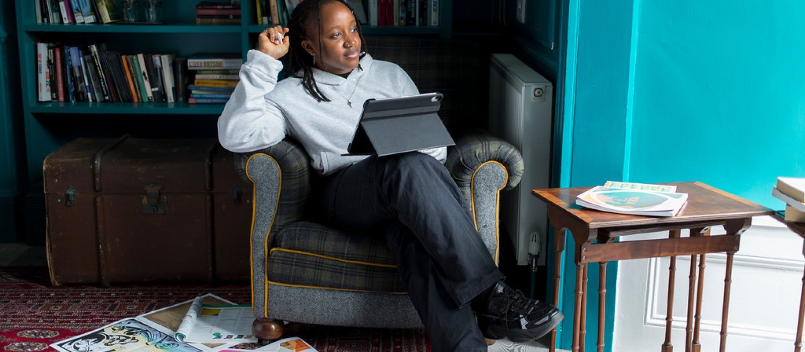 An online student sat in an armchair working on their tablet computer