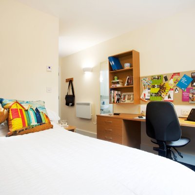 An empty university room, equipped with double bed and desk